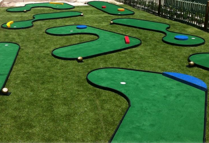 Portable green mini golf holes with black edging and colorful obstacles